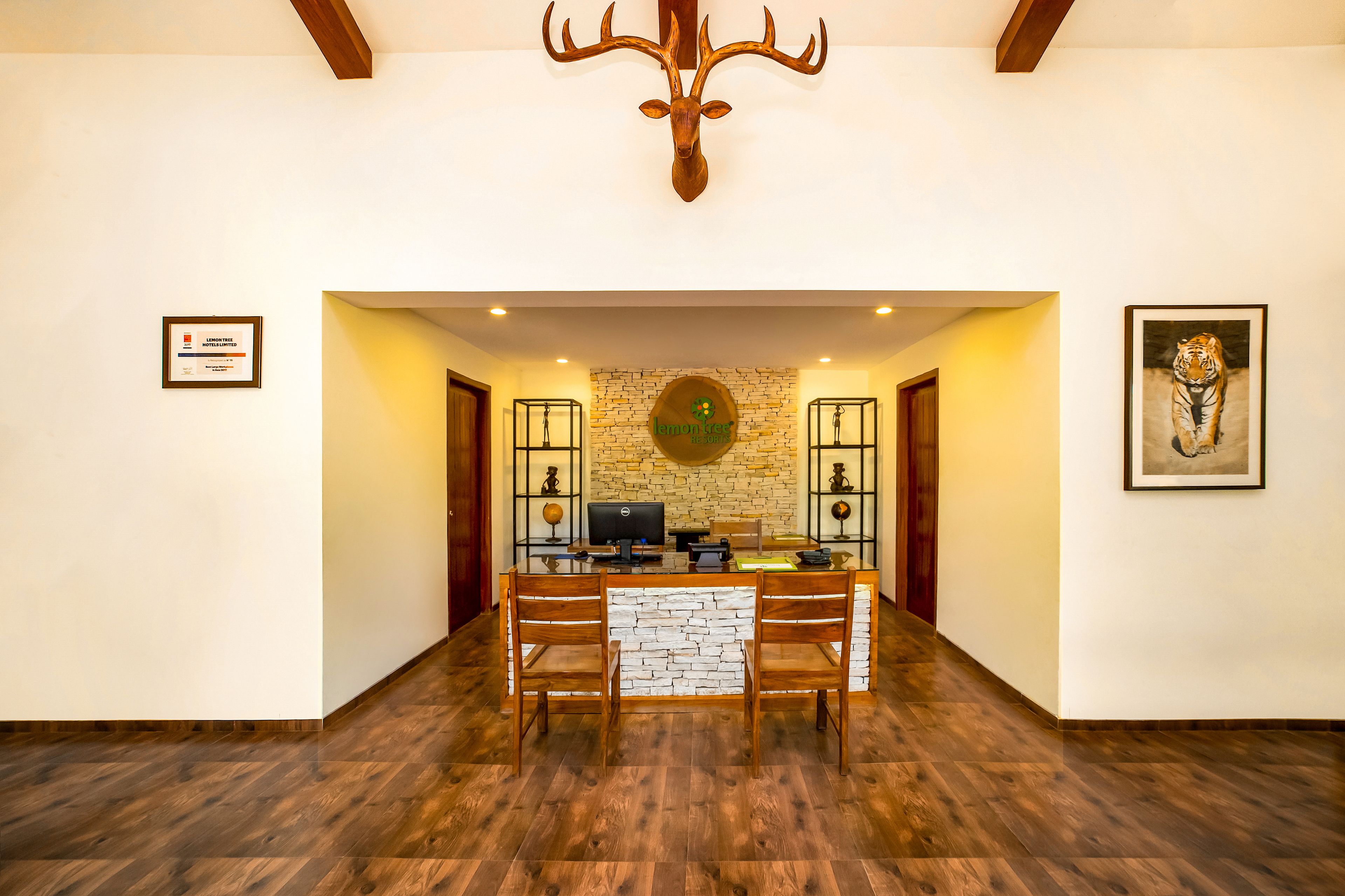 A reception area with a stone wall, a mounted deer head, and a tiger painting.