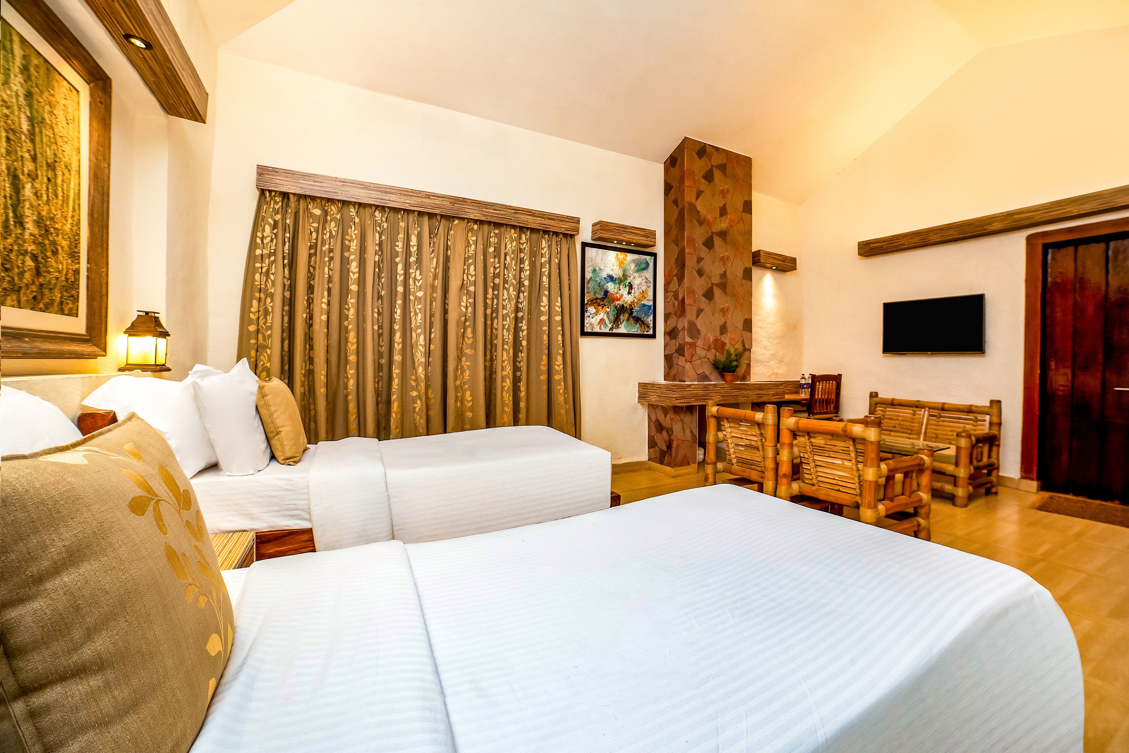 A hotel room with a large bed, a sofa, a dining table with chairs, and a TV mounted on the wall.