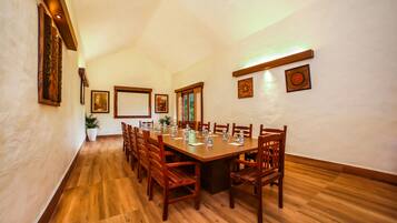 A conference room with a long wooden table, chairs, and framed artwork on the walls.