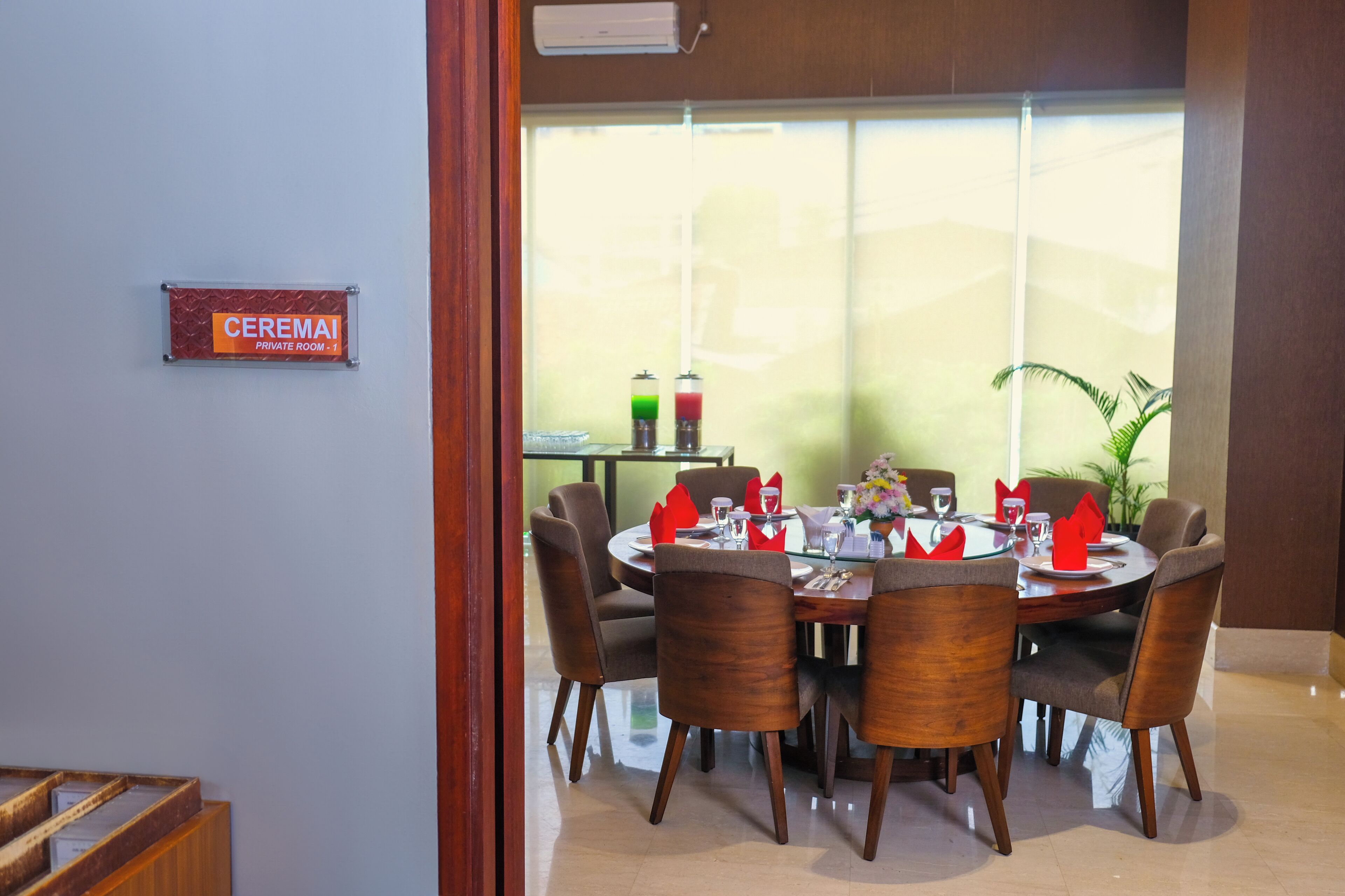 Un salón comedor privado con una mesa redonda, seis sillas y un ventanal con vistas.