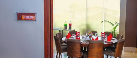 A private dining room with a round table, six chairs, and a large window with a view.
