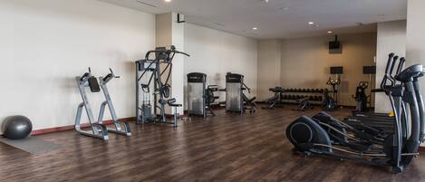 Un gimnasio amplio con diversos equipos de ejercicio, como cintas de correr, elípticas y pesas libres.