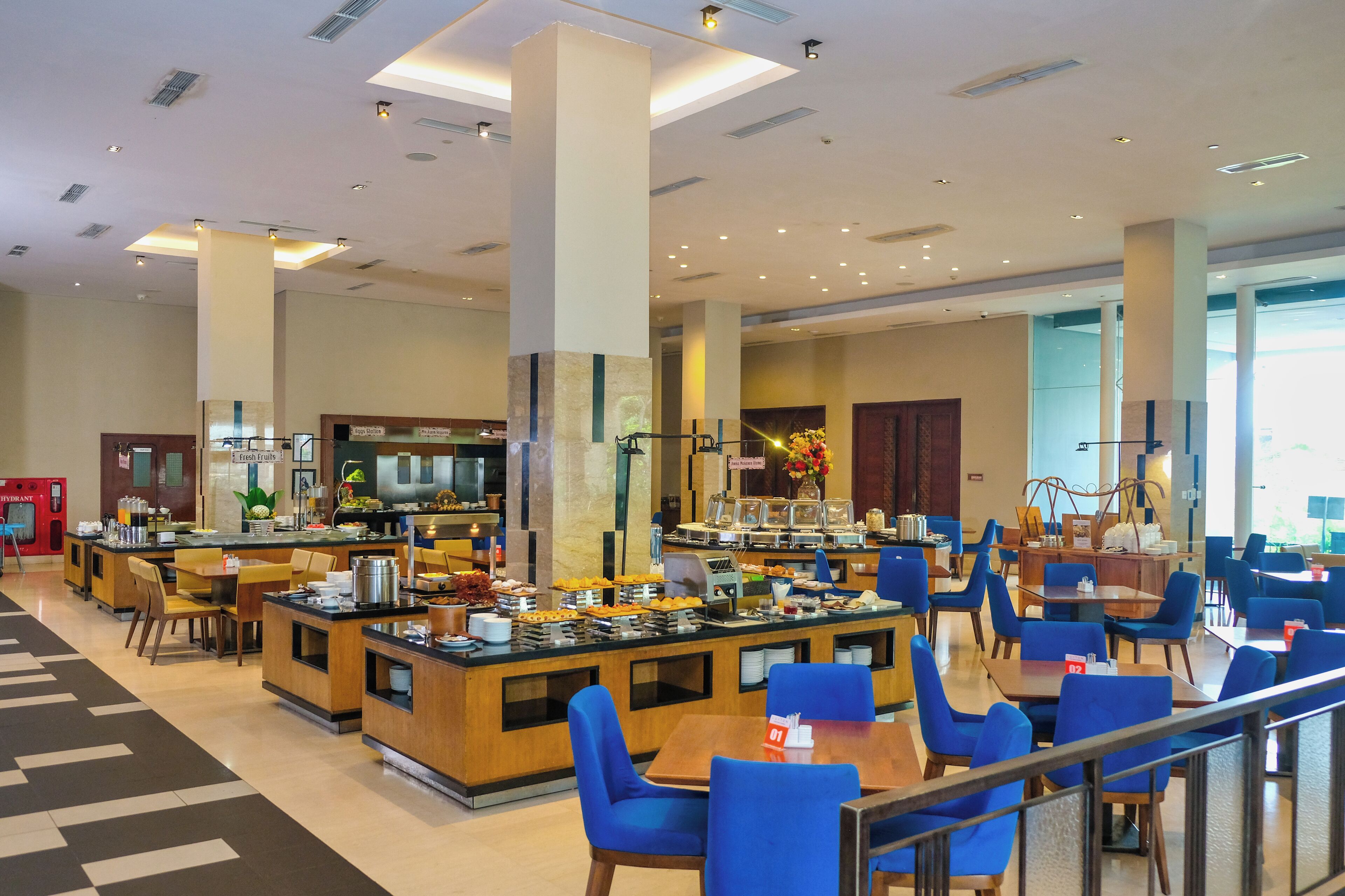 A hotel lobby with a central bar area, multiple seating arrangements, and a staircase leading to an upper level.