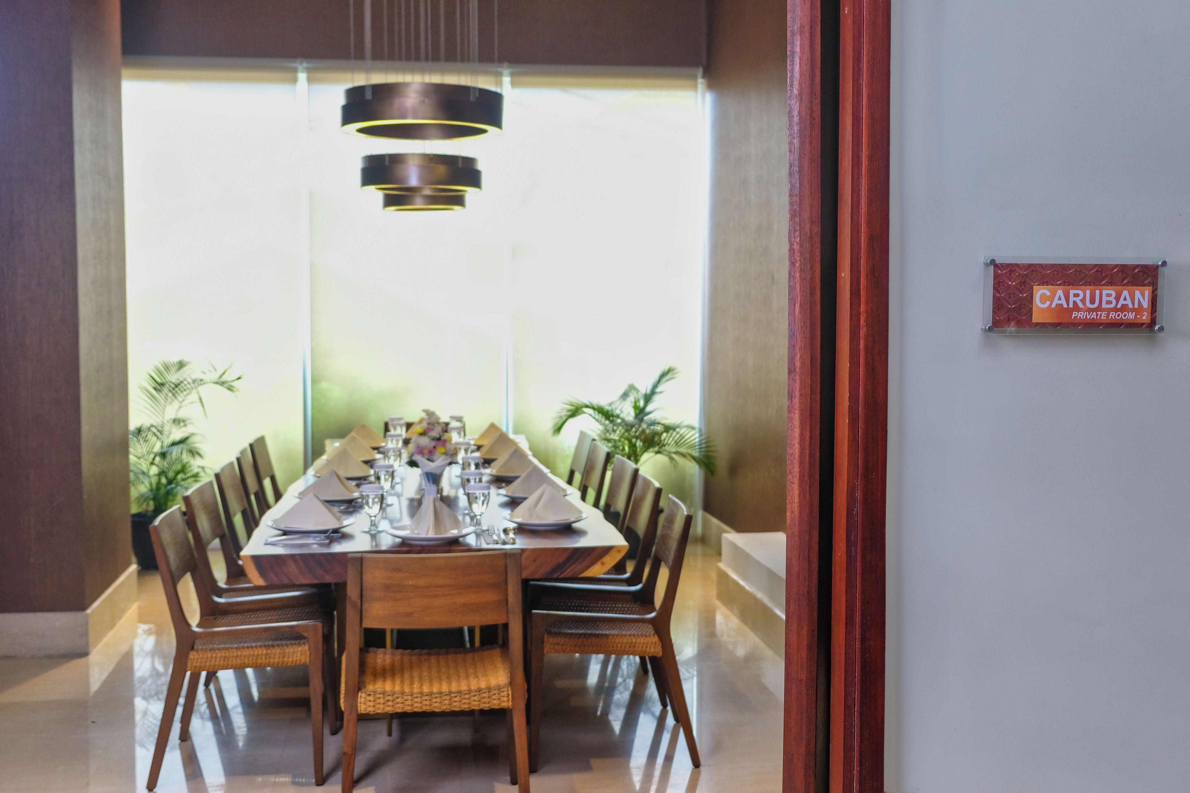Un comedor privado con una larga mesa de madera dispuesta para seis personas, rodeado de sillas de mimbre.