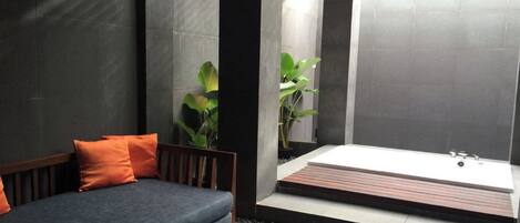 Ein modernes Badezimmer mit Badewanne, einer Couch und Pflanzen.