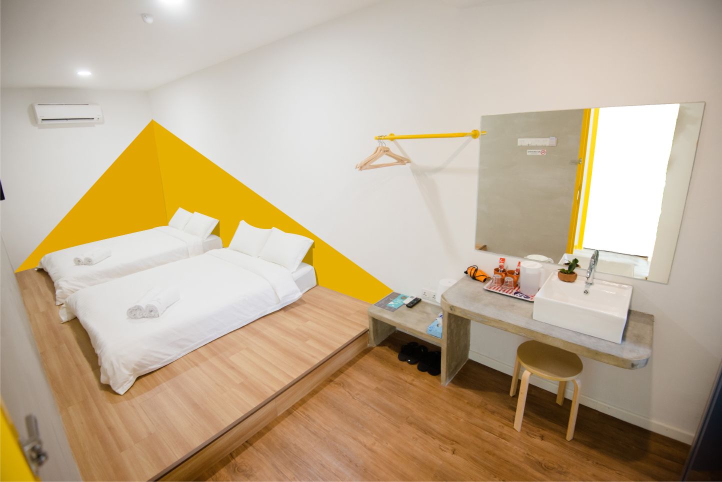 Une chambre d’hôtel avec un lit, un bureau doté d’un lavabo et un miroir.