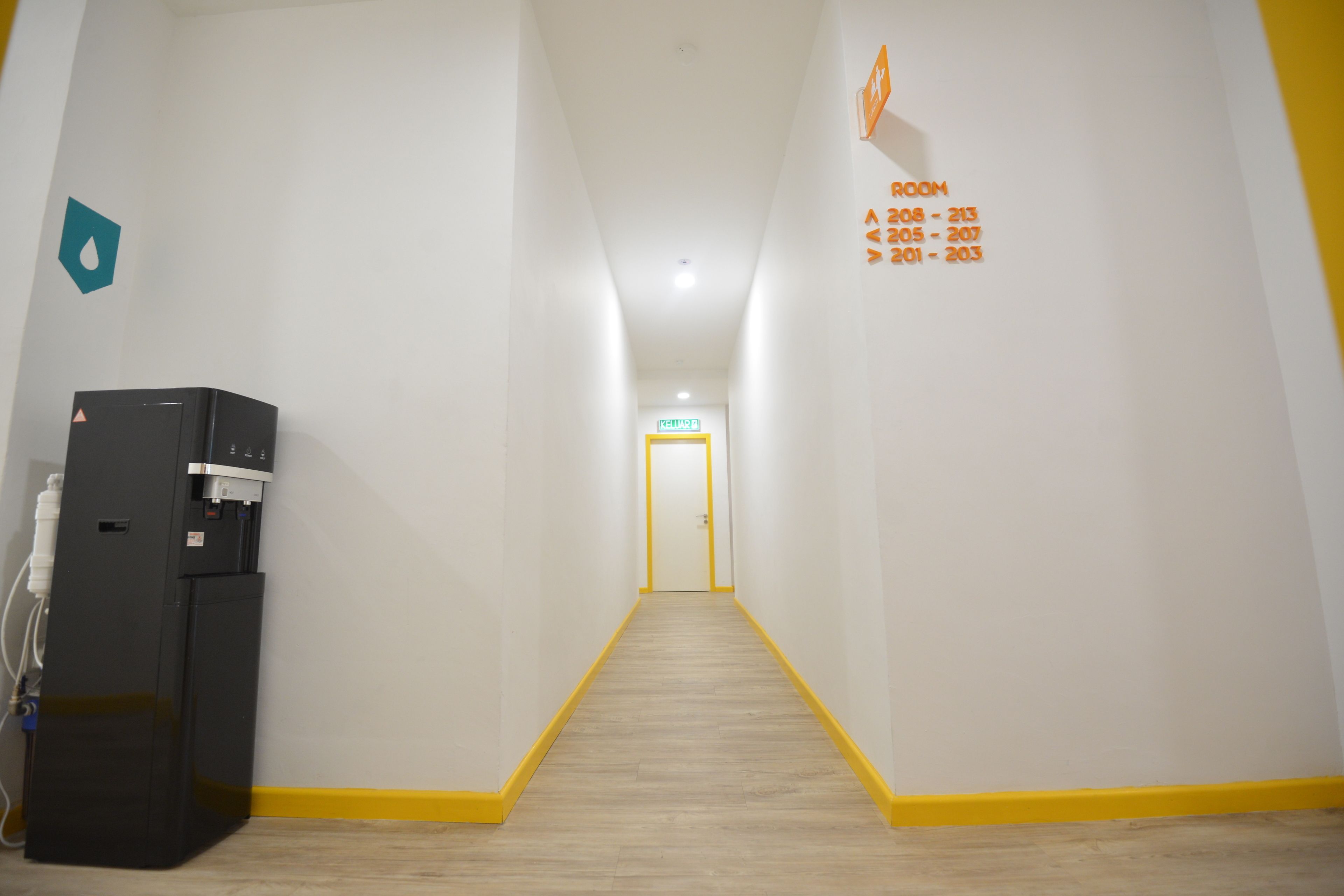 A hallway with a water dispenser on the left, a yellow line marking the floor, and a door at the end with room numbers 208-213, 205-207, 201-203 on the right wall.