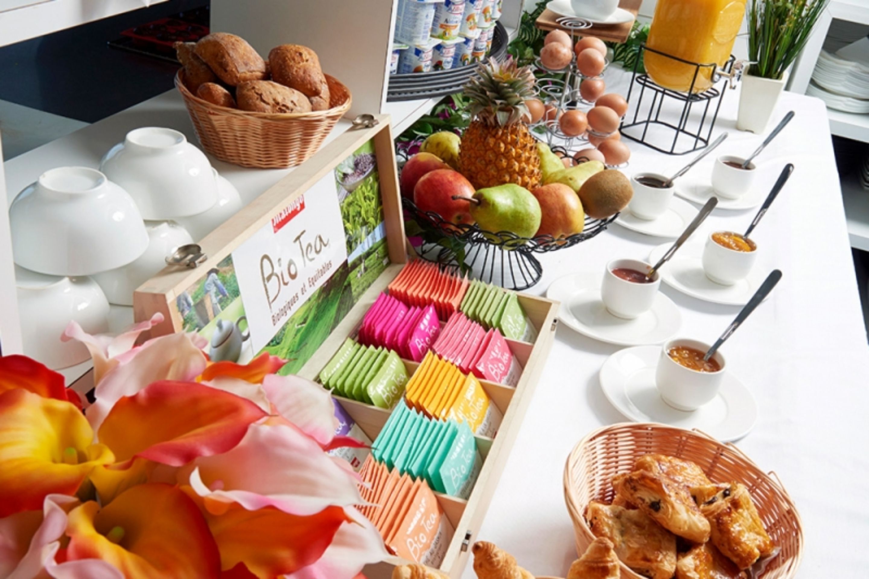 Ein Frühstücksbuffet mit verschiedenen Speisen und einem Schild mit der Aufschrift 'Bio Tee'.