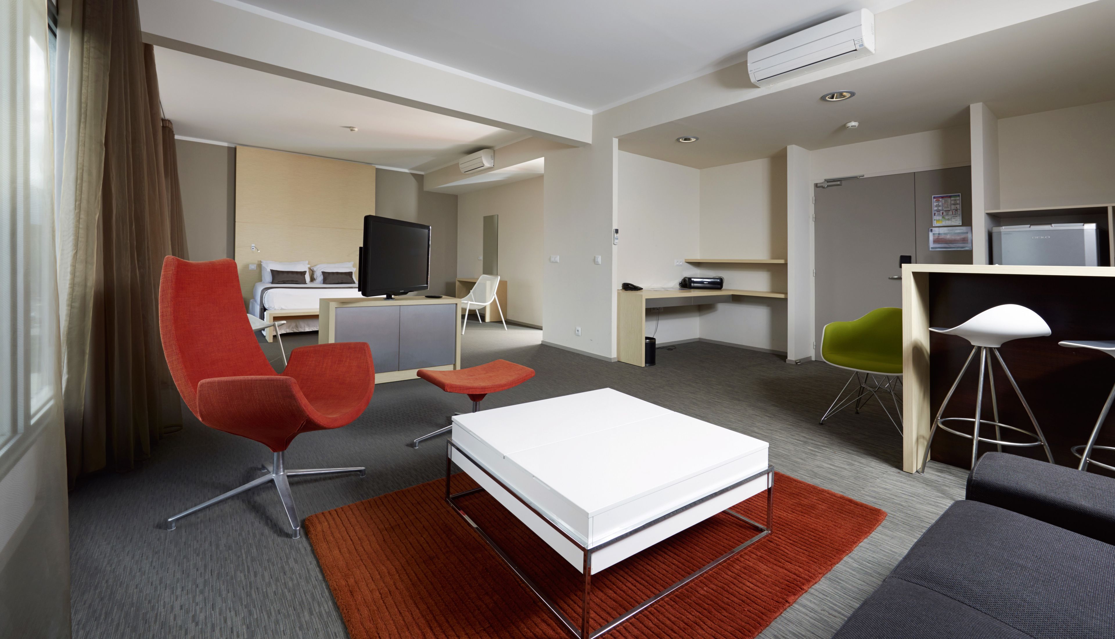 Een hotelkamer met een bed, een televisie, een bureau, een stoel en een bank.