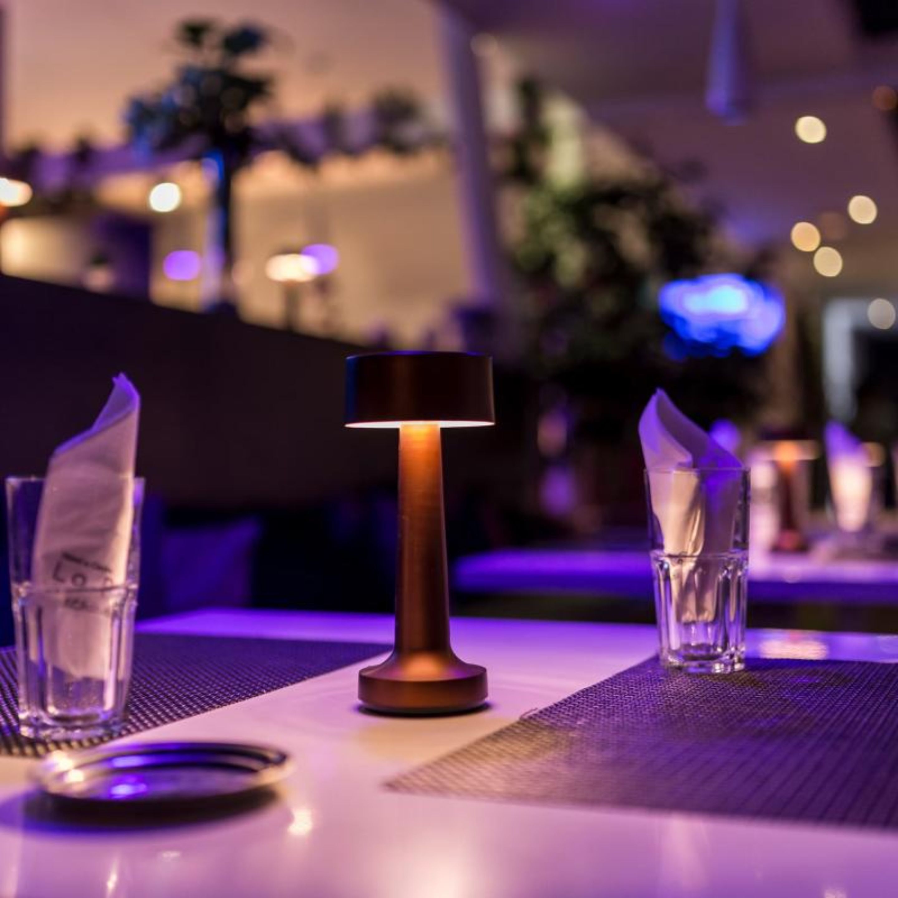 A table set with a candle, two glasses, and a napkin holder.