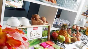 A buffet with various food items including pastries, fruits, and a box of Bio Tea. - L'Hôtel du Centre (Nouméa)