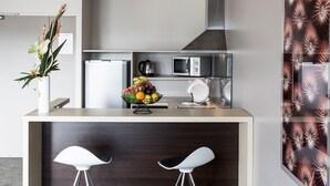 A modern kitchen with a central island, a microwave, a kettle, and a fruit bowl. - L'Hôtel du Centre (Nouméa)