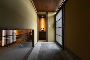 A narrow hallway with a stone floor, wooden ceiling, and sliding doors on one side.