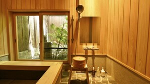 A wooden spa room with a large bathtub, a wooden stool, and a shower area. - Kuraya Kiyomizu-Gojo (Kyoto)