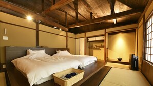 A traditional Japanese-style room with tatami flooring, two beds with white bedding, a woven basket on the floor, and a sliding door. - Kuraya Kiyomizu-Gojo (Kyoto)