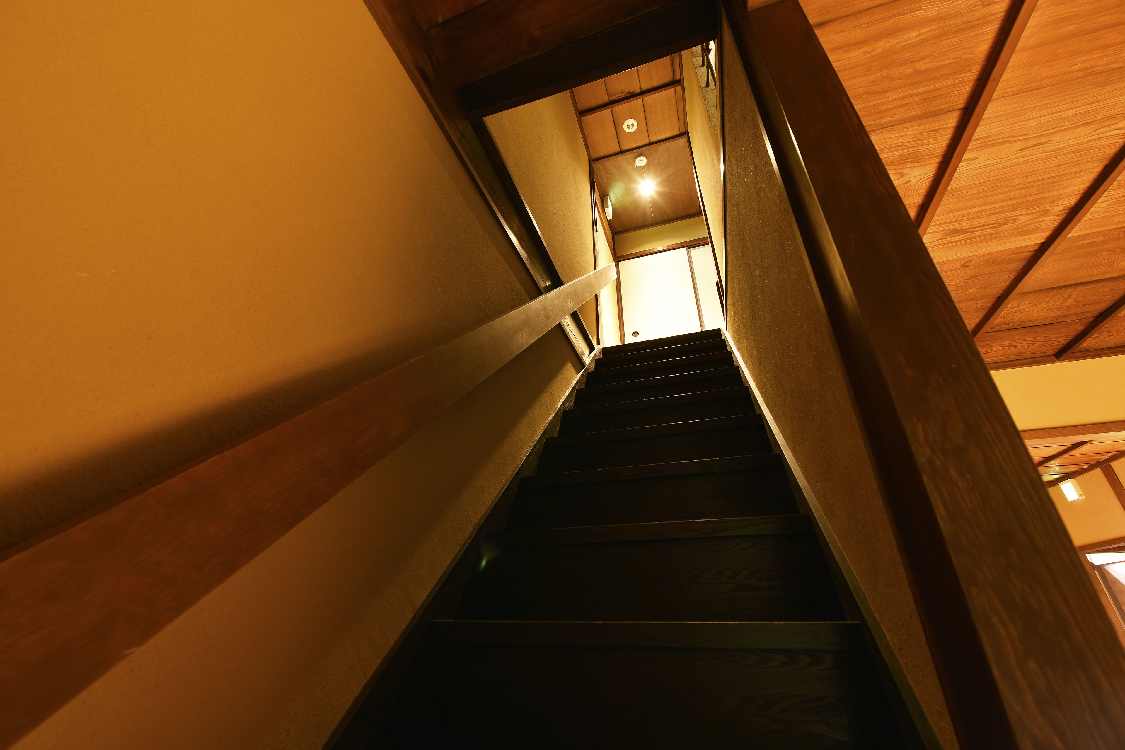 Un escalier avec des rampes en bois et un luminaire au sommet.