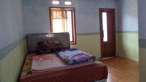 A bedroom with a bed, a window with curtains, a door, and a ceiling light fixture. - Yog Bromo Homestay (Ngadisari)