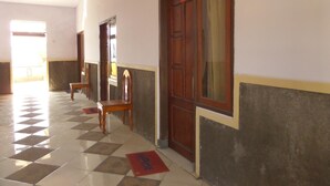 A hallway with tiled flooring, wooden doors, and benches. - Yog Bromo Homestay (Ngadisari)