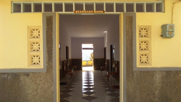 A hallway leading to a standard room with patterned floor tiles and decorative wall panels. - Yog Bromo Homestay (Ngadisari)