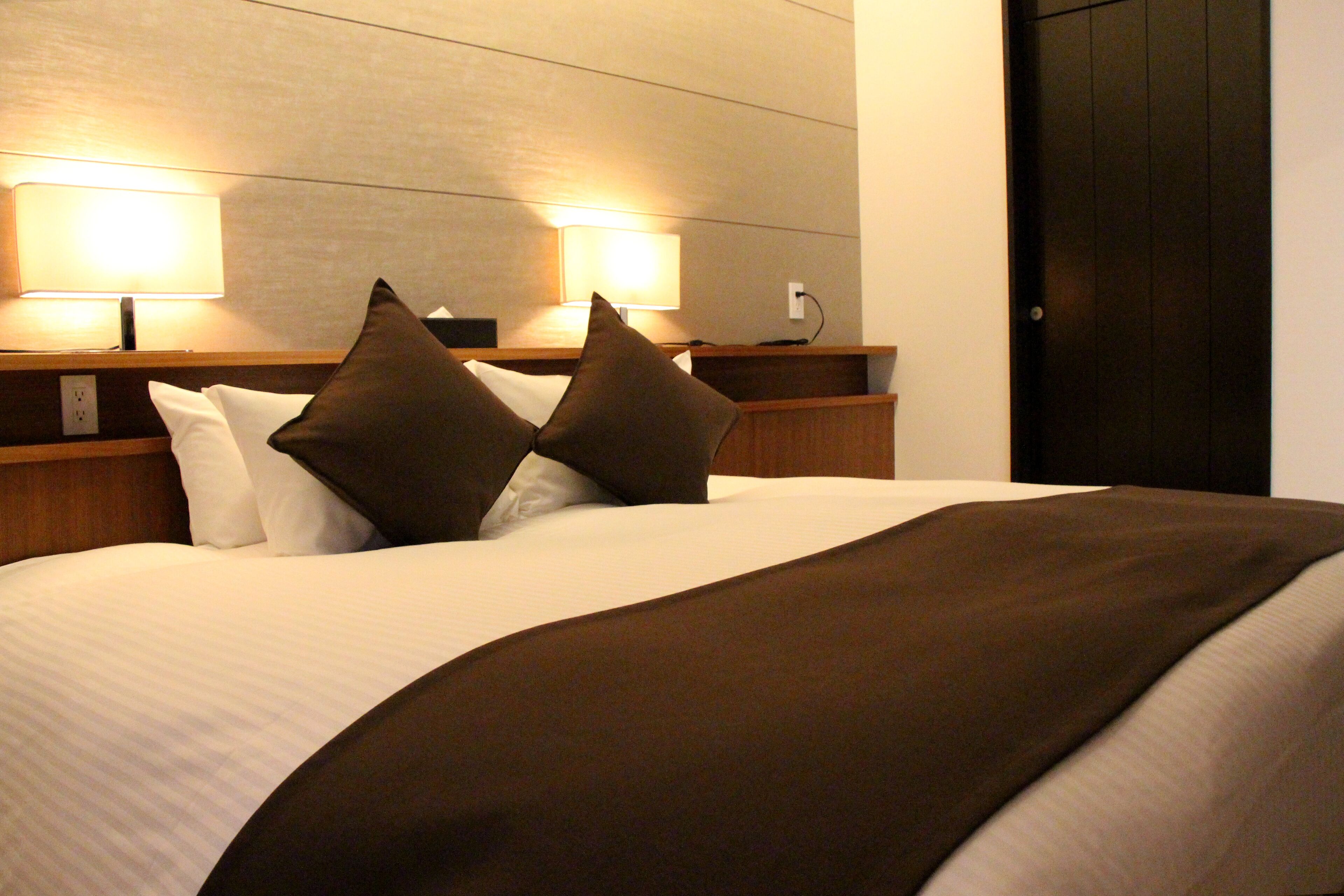 Una habitación de hotel con una cama grande, dos lámparas de noche y un cabecero de madera oscura.