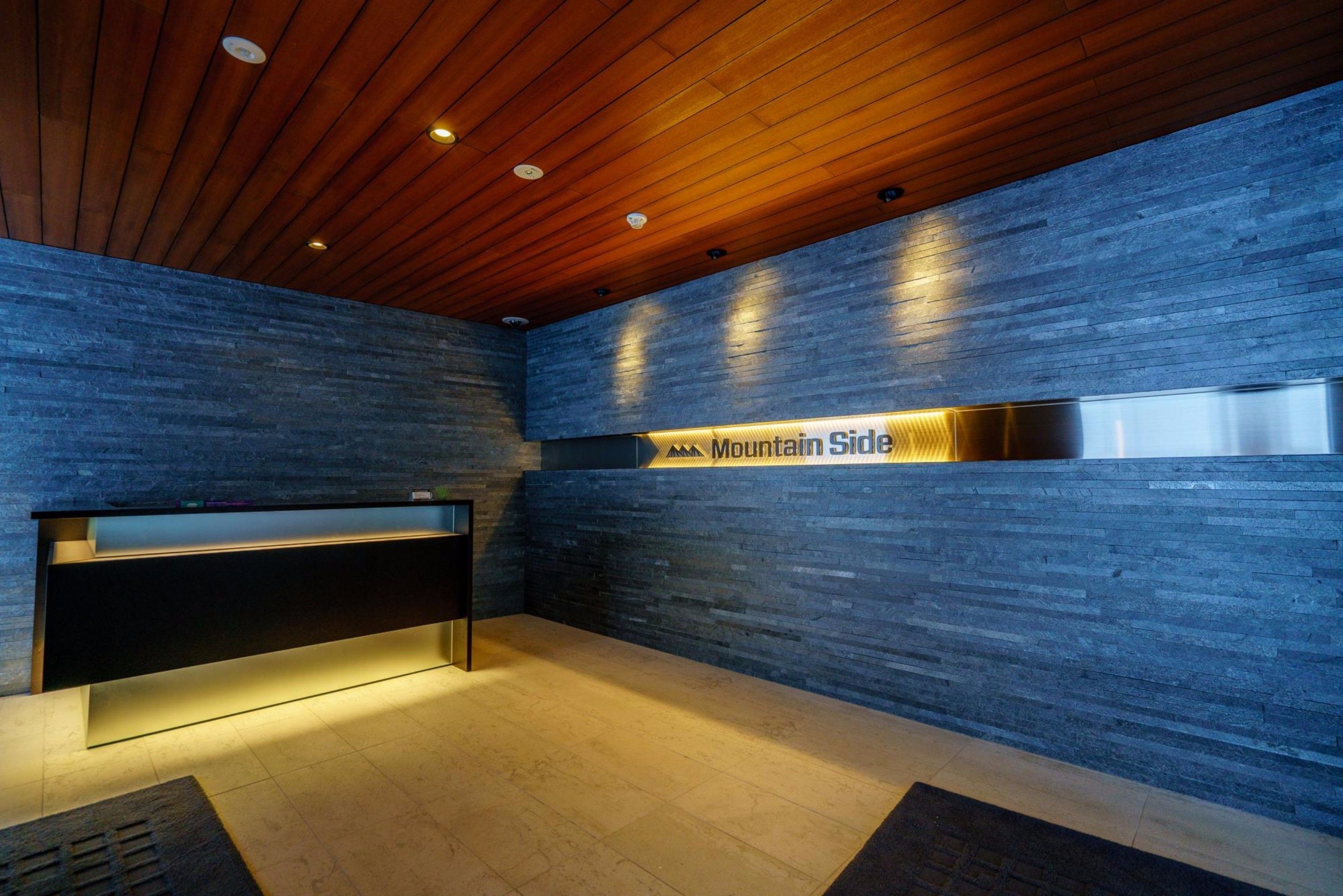 A reception area with a wooden ceiling, a reception desk, and a wall with a 'Mountain Side' sign.