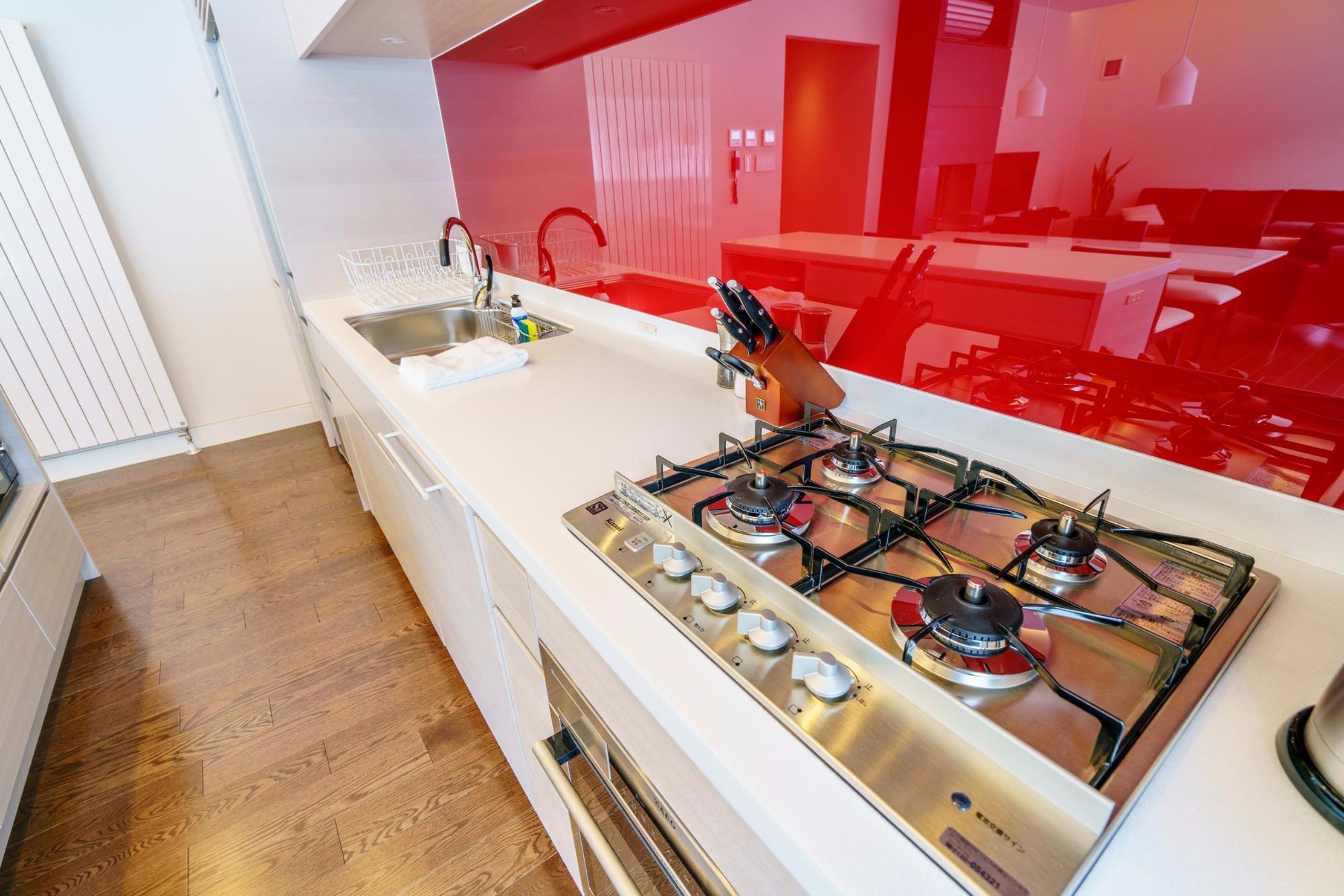 A modern kitchen with a gas stove, stainless steel sink, and wooden flooring.