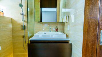 A modern bathroom with a glass-enclosed shower, a white sink, and a wooden cabinet.