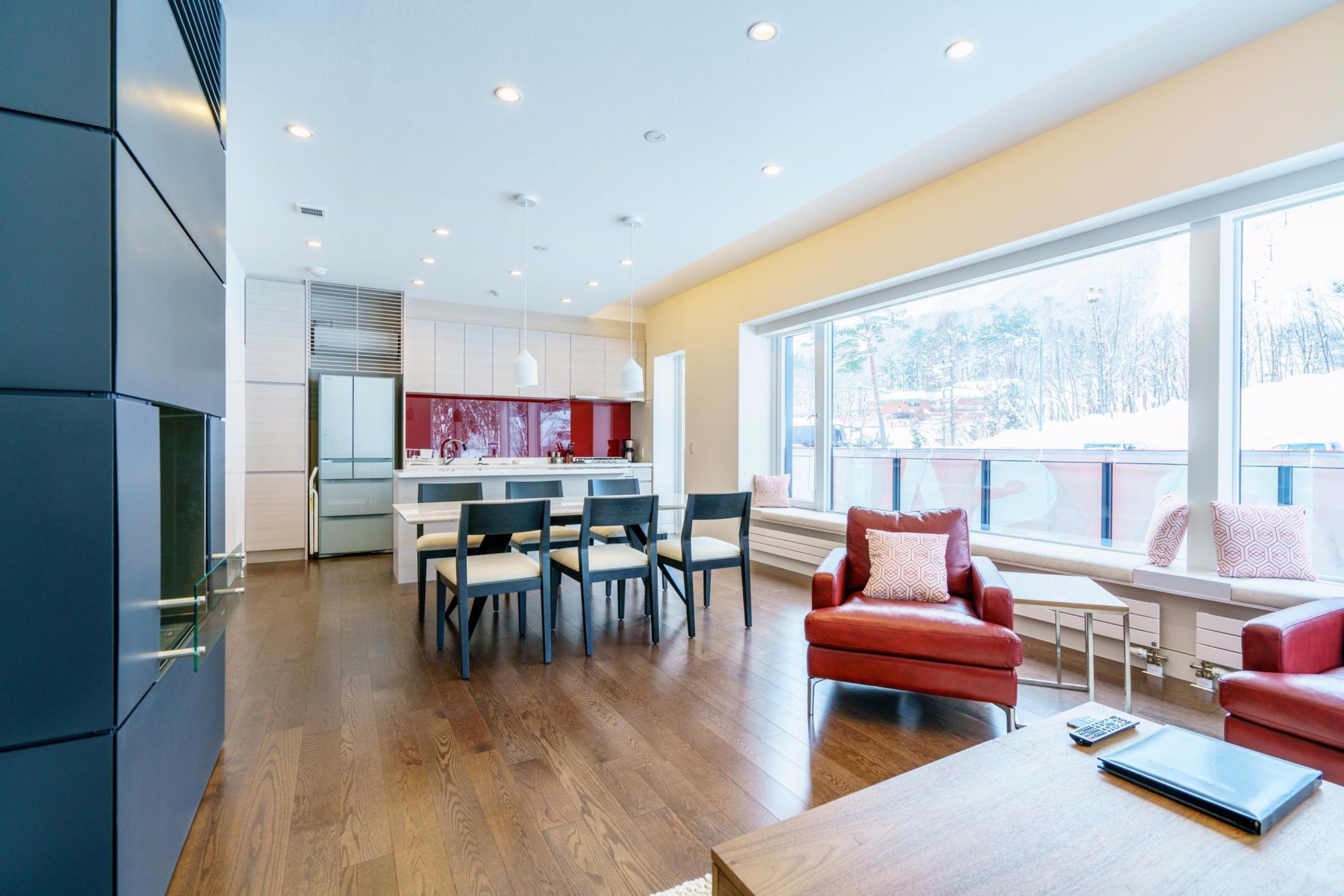 Una cocina moderna con comedor, ventanas amplias y un sofá rojo.