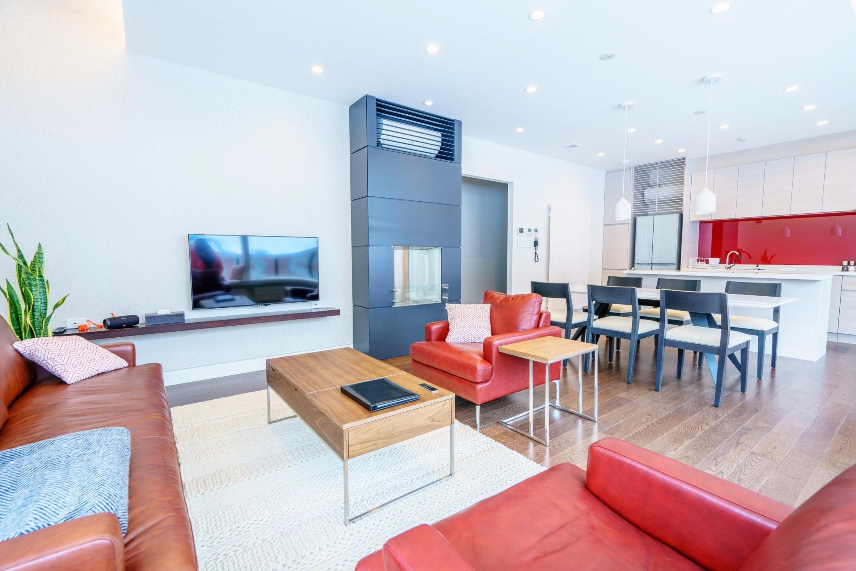 A modern living room with a red sofa, a coffee table, and a TV mounted on the wall.