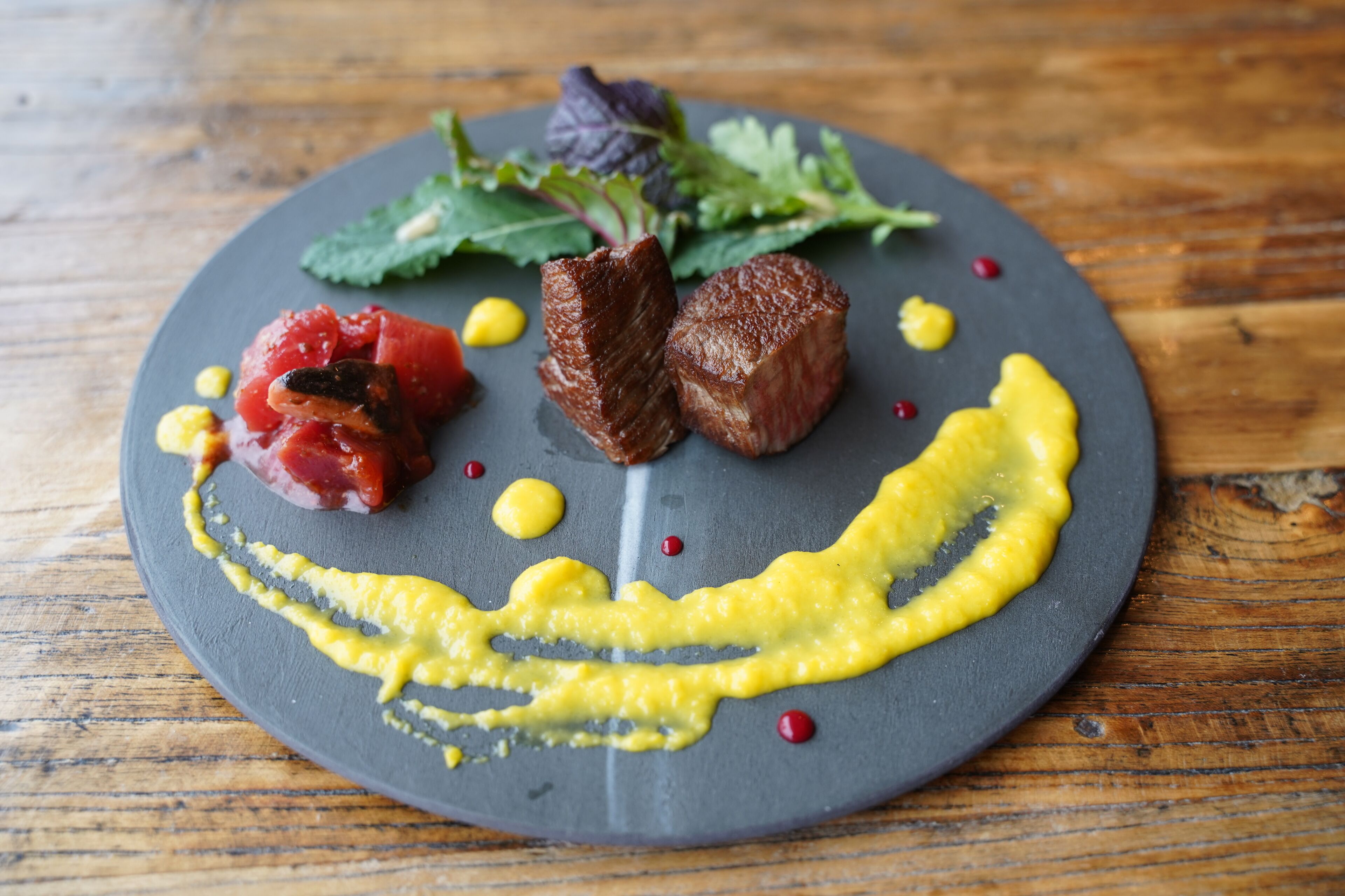Un piatto con carne, verdure e salsa.