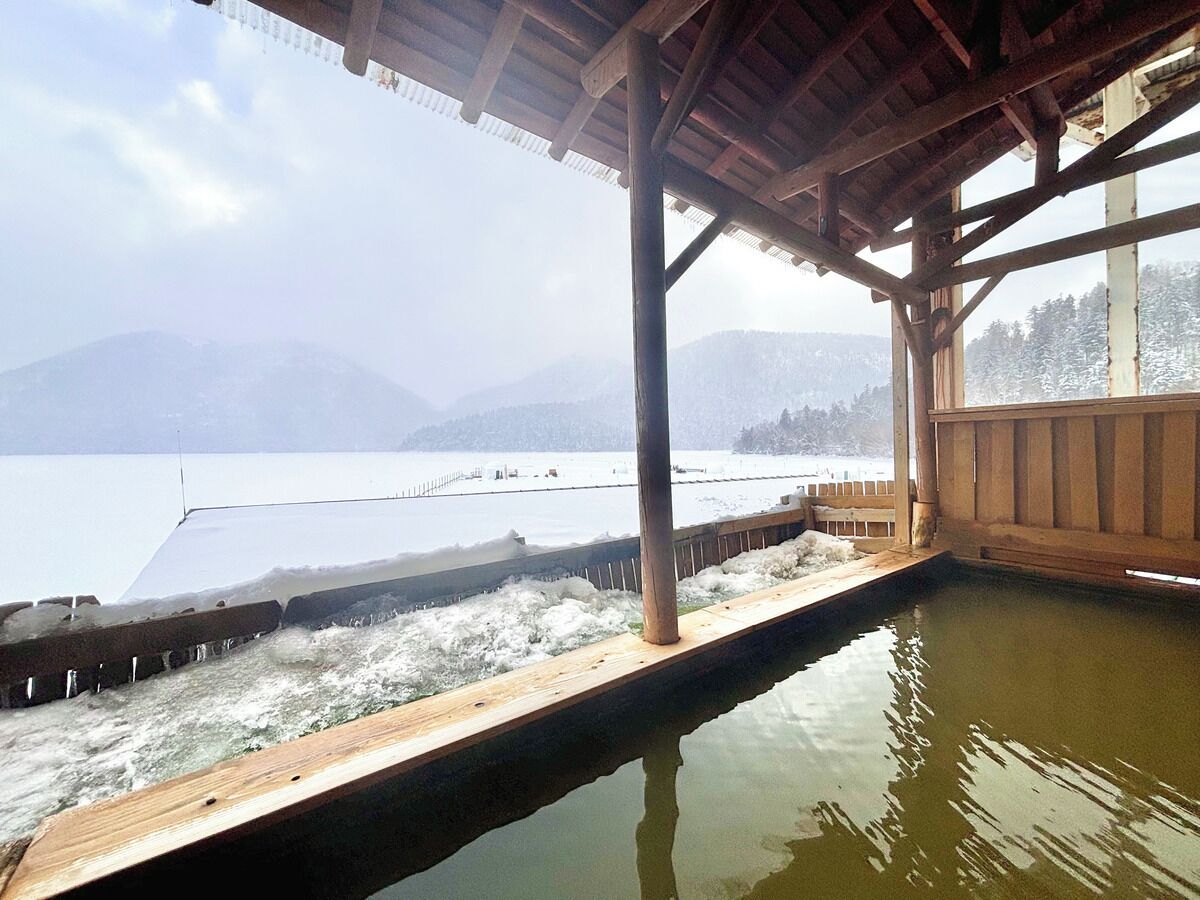 A wooden deck overlooking a calm body of water with mountains in the background.