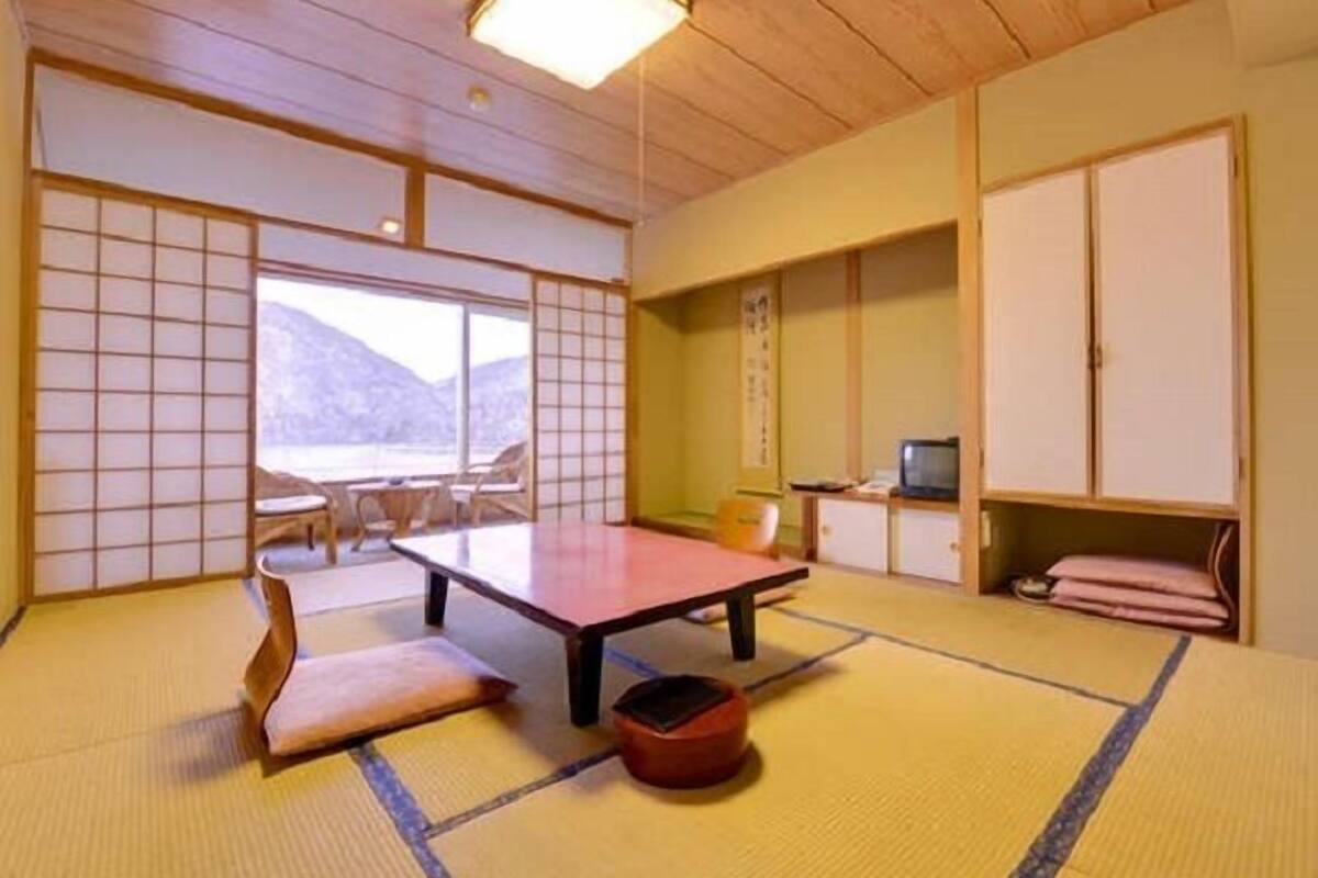 Une pièce de style japonais traditionnel, avec un sol recouvert de tatamis, une table basse et des portes coulissantes.