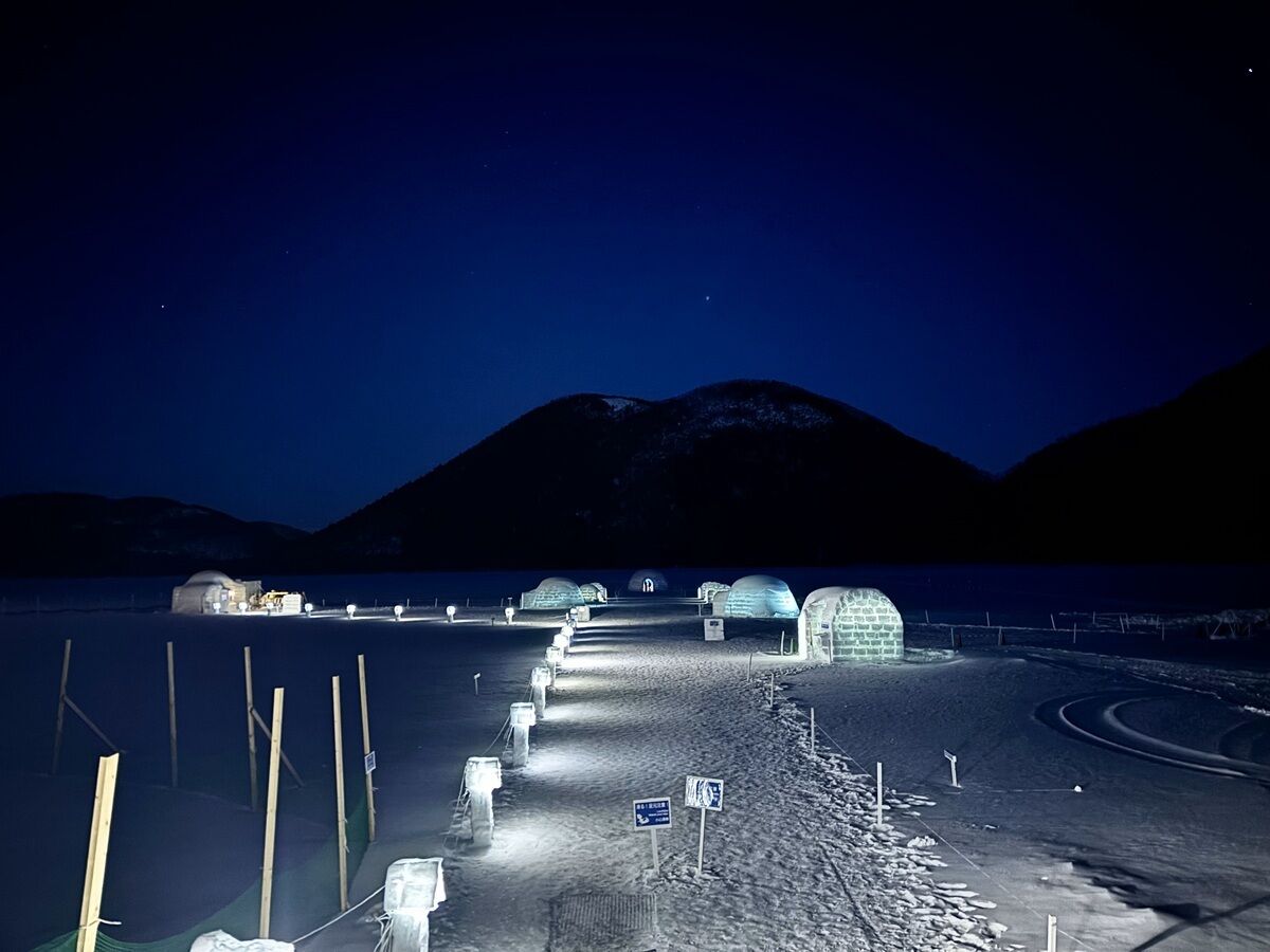 Una serie de iglús unidos por un sendero en un paisaje nevado de noche.