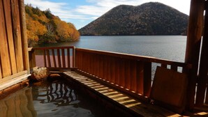 A wooden deck with a view of a lake and mountains. - Shikaribetsu Lakeside Onsen Hotel Fusui (Shikaoi)