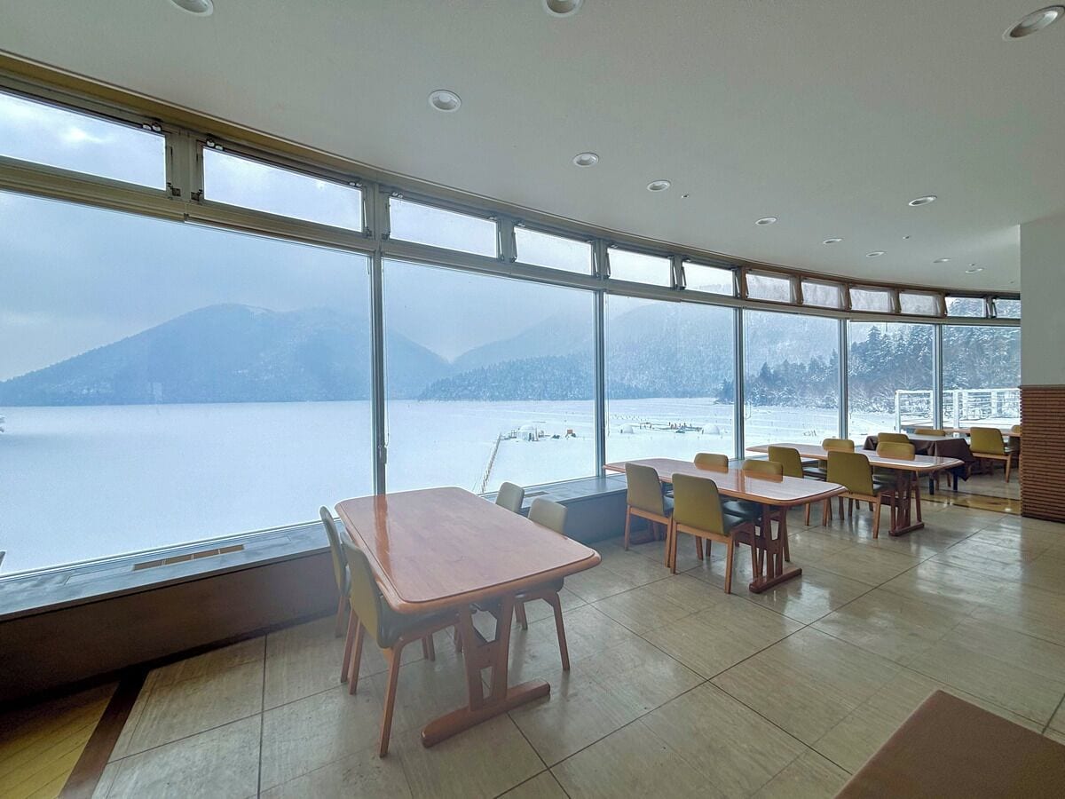A dining area with large windows overlooking a body of water and mountains.