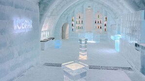 An ice bar with shelves of bottles, ice sculptures, and a neon sign. - Shikaribetsu Lakeside Onsen Hotel Fusui (Shikaoi)