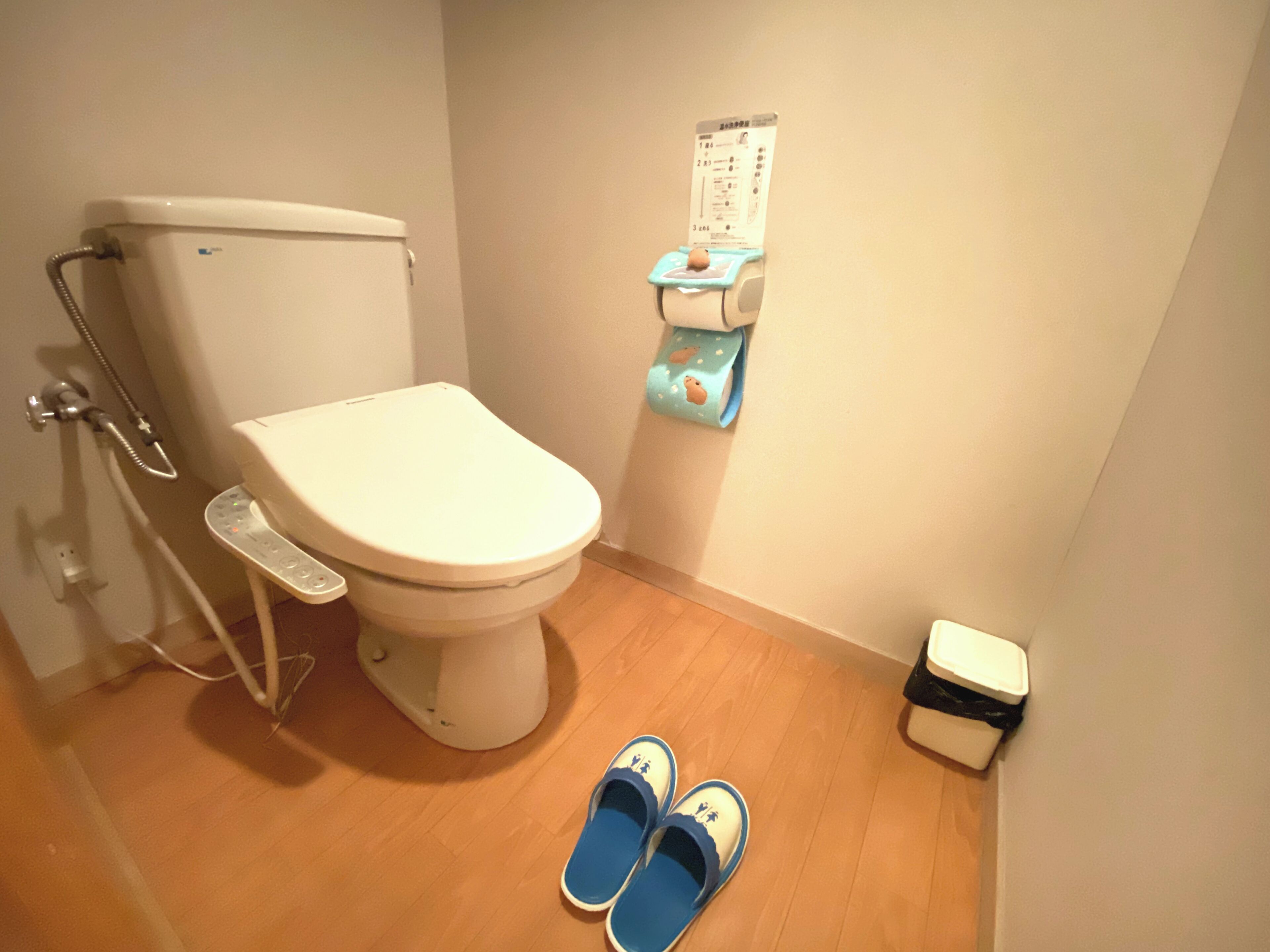A bathroom with a toilet, a shower, and a waste bin.