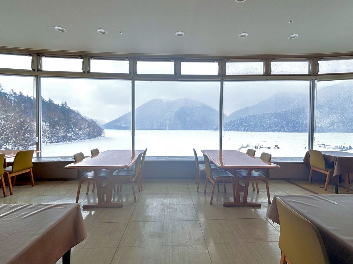 Una sala conferenze con ampie finestre vista su un lago e montagne.