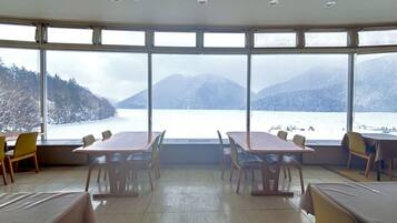 Una sala conferenze con ampie finestre vista su un lago e montagne.