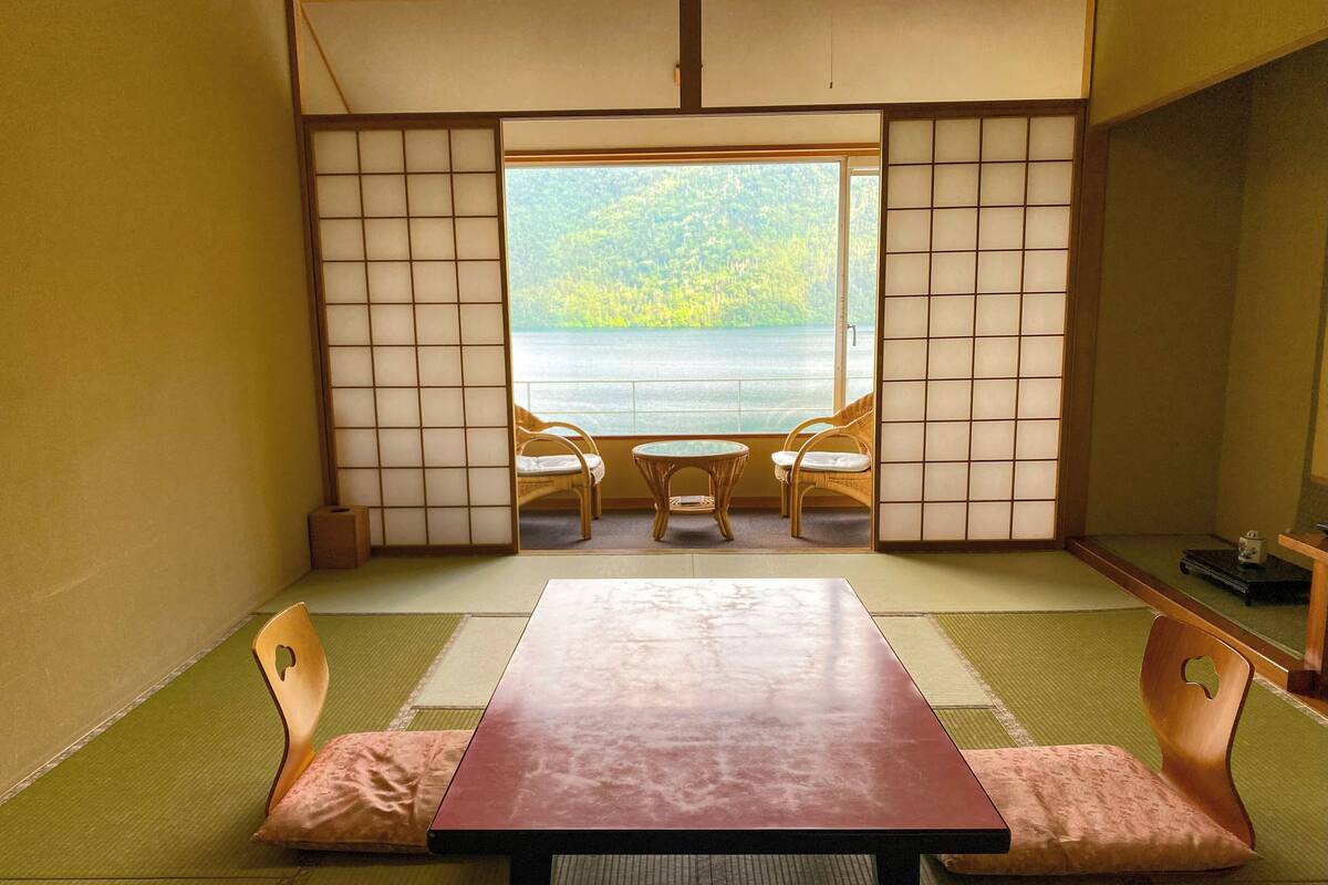 Une pièce de style japonais traditionnel, avec un sol recouvert de tatamis, une table basse et deux chaises.