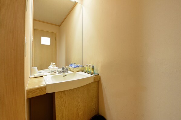 A bathroom with a wooden vanity, a sink, and a mirror. - Kanko Hotel Tamaru (Nara)