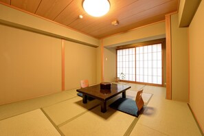 A traditional Japanese room with tatami flooring, a low table, and sliding doors. - Kanko Hotel Tamaru (Nara)