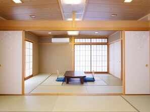 A traditional Japanese room with tatami flooring, a low table, and sliding doors. - Kanko Hotel Tamaru (Nara)