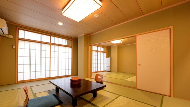 Una habitación japonesa tradicional con suelo de tatami, una mesa baja con cojín y puertas correderas.