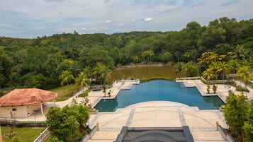 A resort with a large swimming pool surrounded by lush greenery and a small lake.