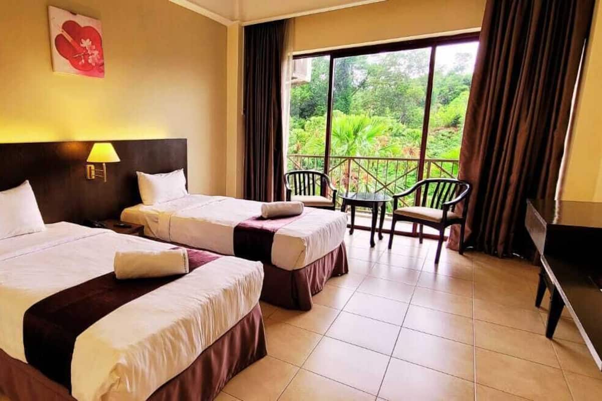 A hotel room with two beds, a balcony with chairs, and a TV.