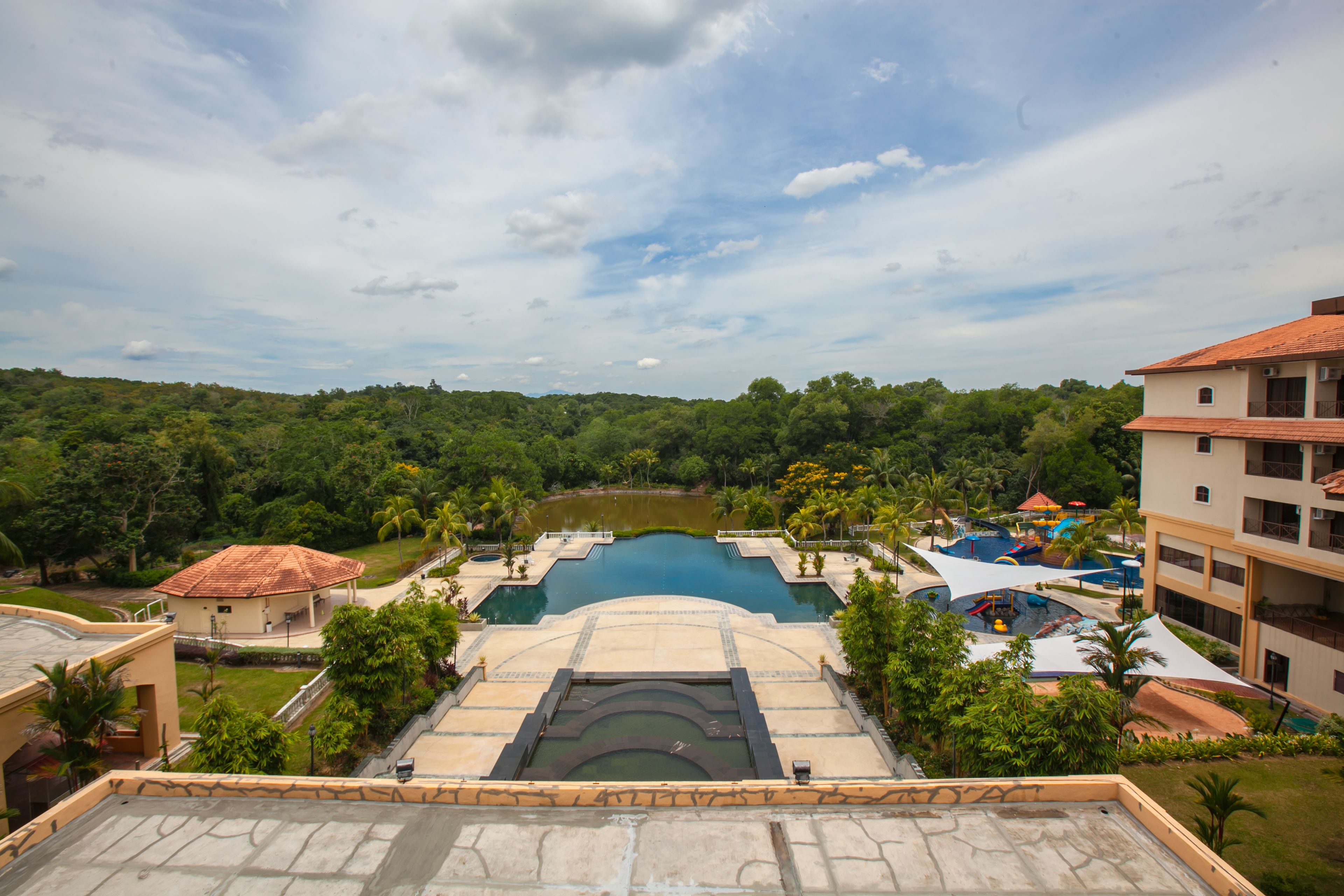 Un resort con una amplia piscina, varias toboganes acuáticos y exuberante vegetación alrededor.