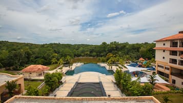 Un resort con una amplia piscina, varias toboganes acuáticos y exuberante vegetación alrededor.