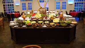A buffet setup with various dishes and a central decorative vase. - Amverton Heritage Resort (Malacca City)