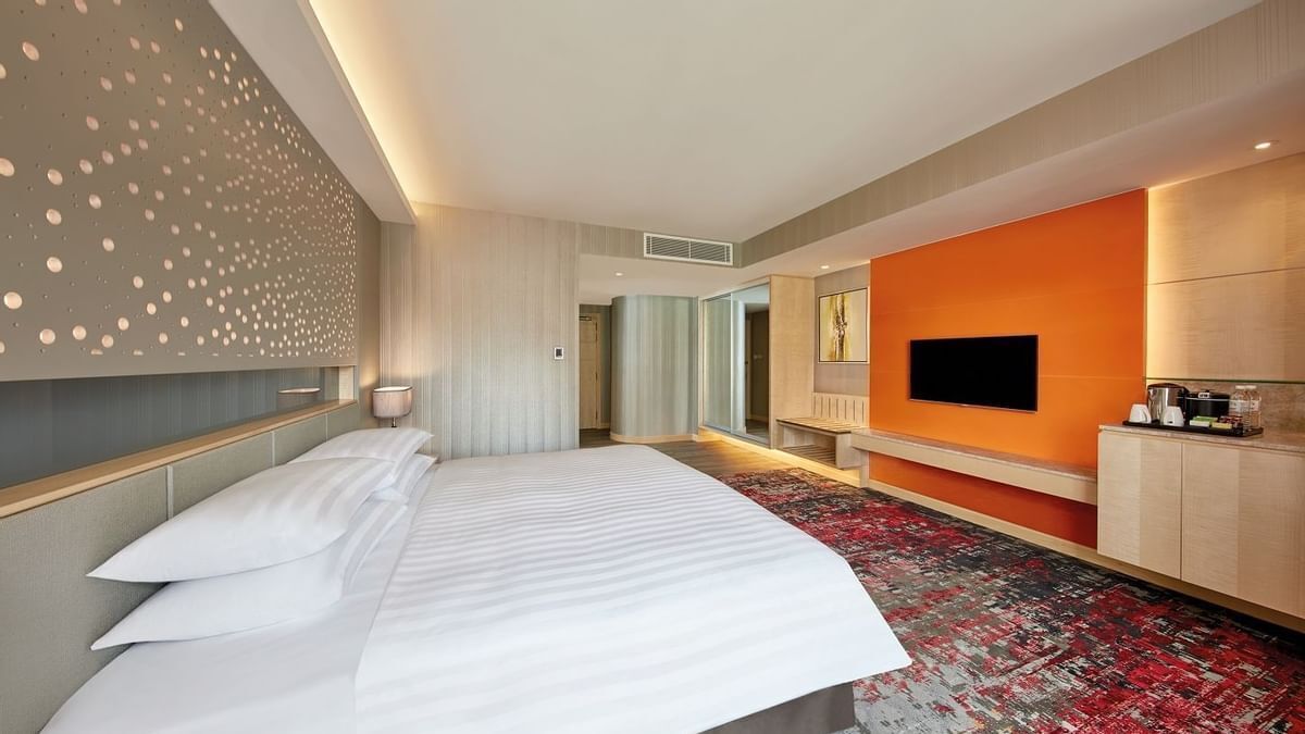 Ein Hotelzimmer mit einem großen Bett, einem Fernseher, einem Schreibtisch und moderner Einrichtung.